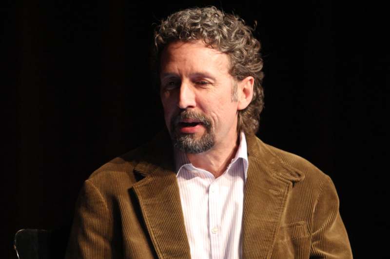 a man with a beard and mustache wearing a brown jacket