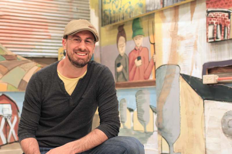 a man sitting in front of a mural