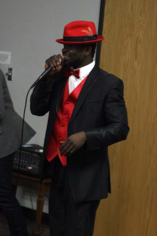 a man in a suit and hat singing into a microphone