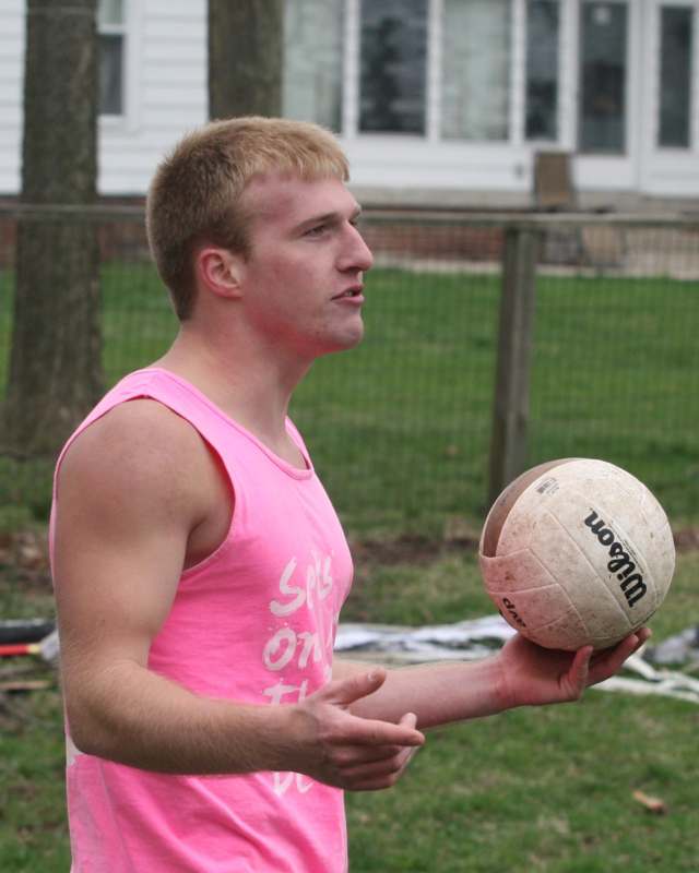 a man in a pink tank top holding a ball