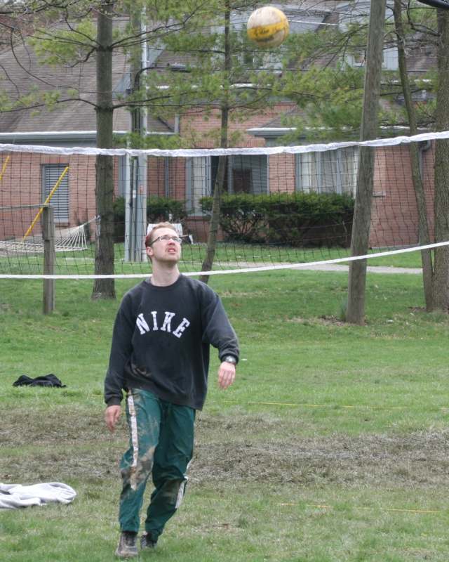 a man standing on grass near a volleyball net