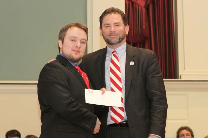 a man holding a piece of paper with another man in a suit