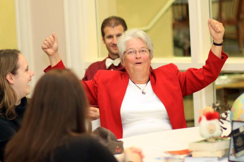 a woman in red jacket sitting at a table with her hands up