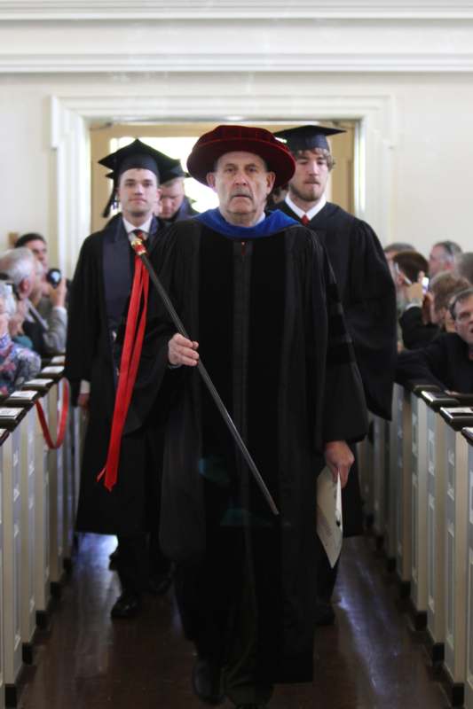 a man in a robe and cap holding a staff
