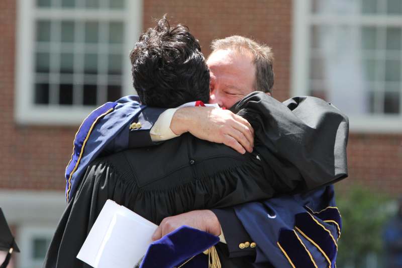 a man in a robe hugging another man