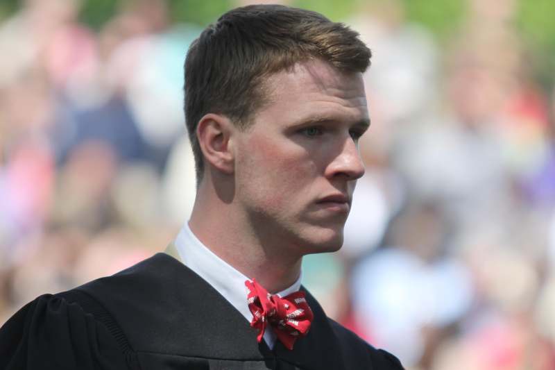 a man in a black robe and red bow tie