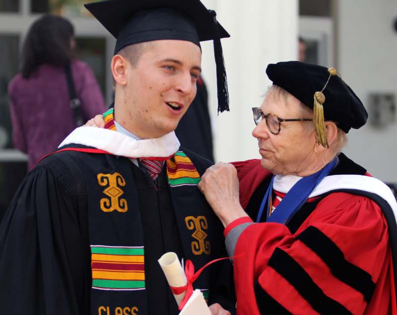 a man in graduation gown and cap standing next to a woman