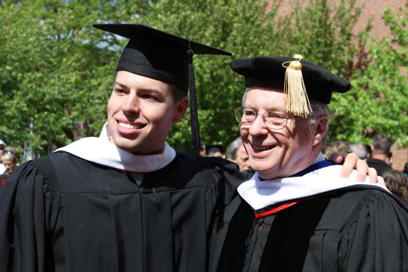 a man in black gowns and cap and gowns smiling