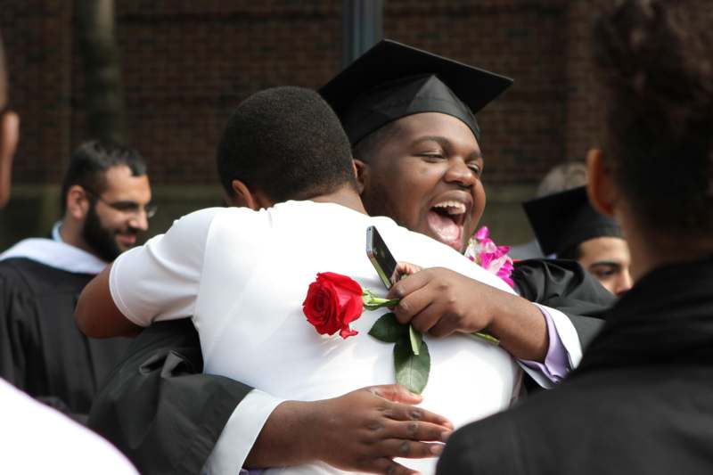 a man in a graduation cap hugging another man
