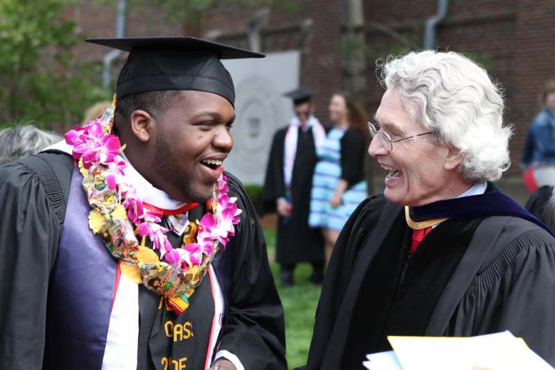 a man in graduation gowns and cap laughing