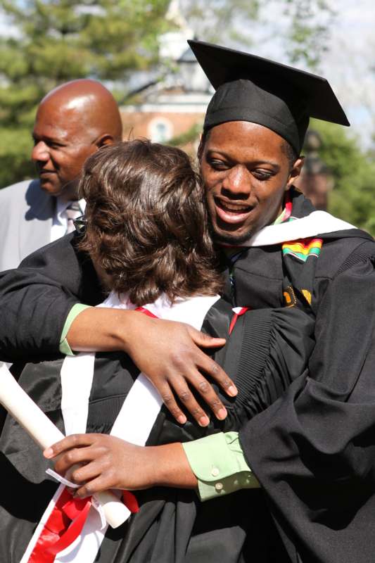 a man in a graduation cap hugging a woman