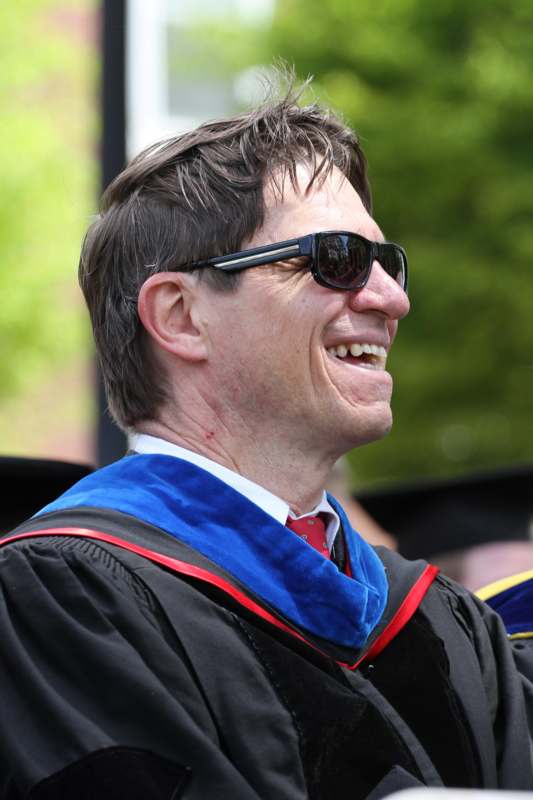 a man wearing sunglasses and a graduation gown