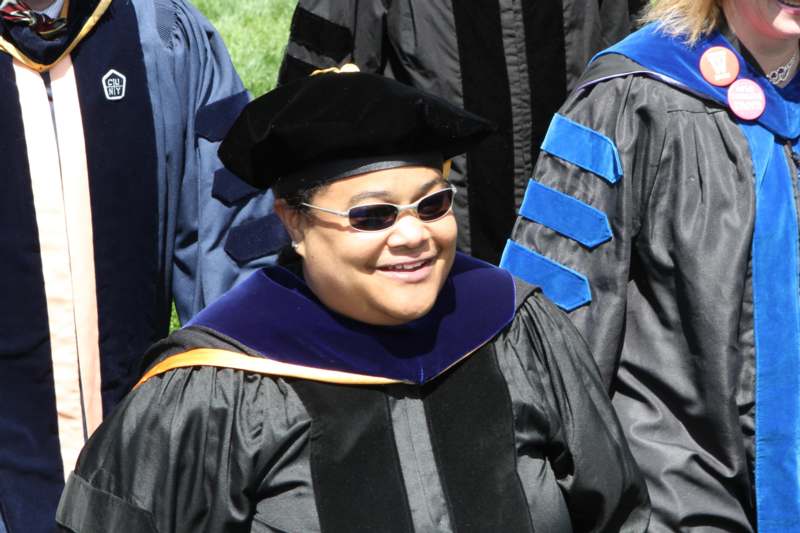 a woman wearing a black graduation gown and sunglasses
