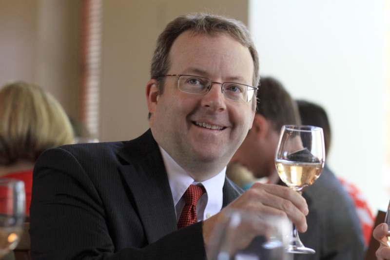 a man in a suit and tie holding a glass of wine