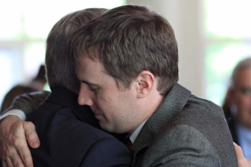 a man in suit hugging another man
