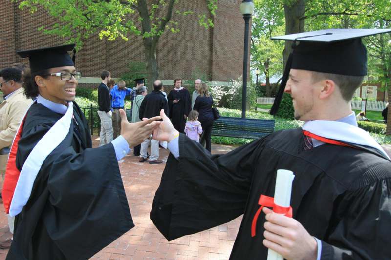 a man in black gowns and cap shaking hands with another man in black gowns and cap