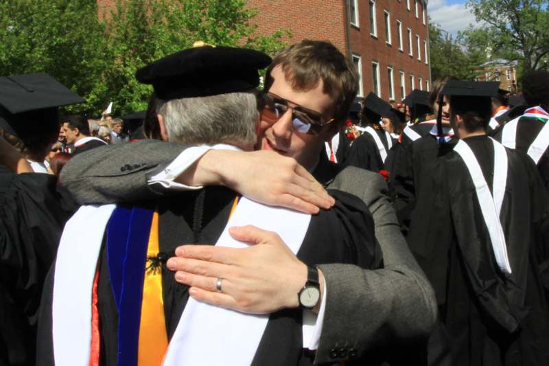 a man hugging a man in a graduation gown