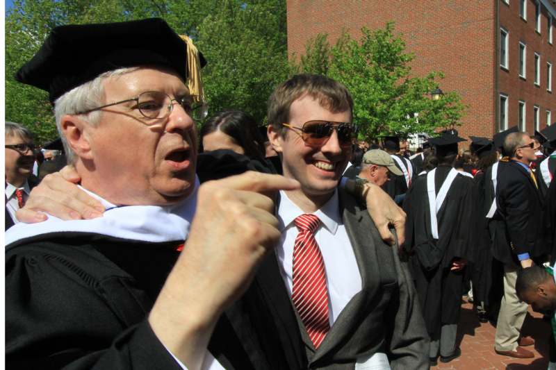 a man in a cap and gown pointing at another man
