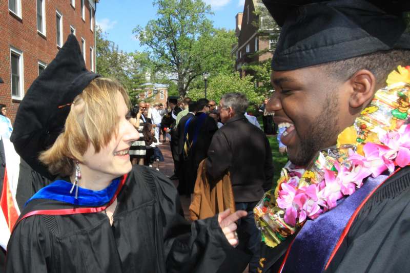 a man and woman in graduation gowns and cap laughing