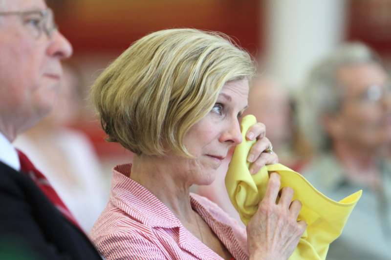 a woman wiping her face with a yellow cloth