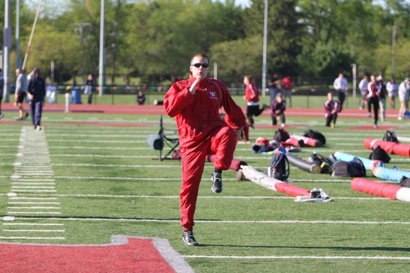 a man in red tracksuit running on a football field