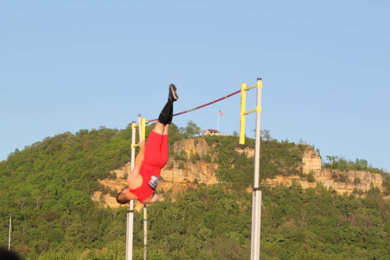 a man in red jumps over a pole