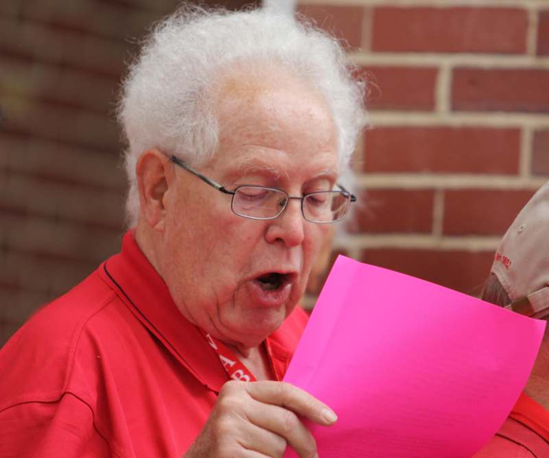 a man in a red shirt reading a pink paper