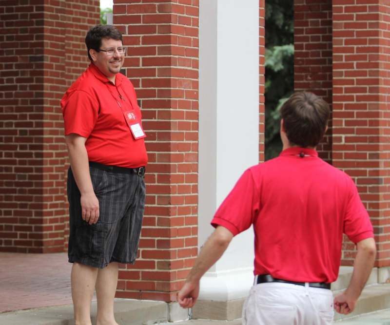 a man in red shirt standing next to another man