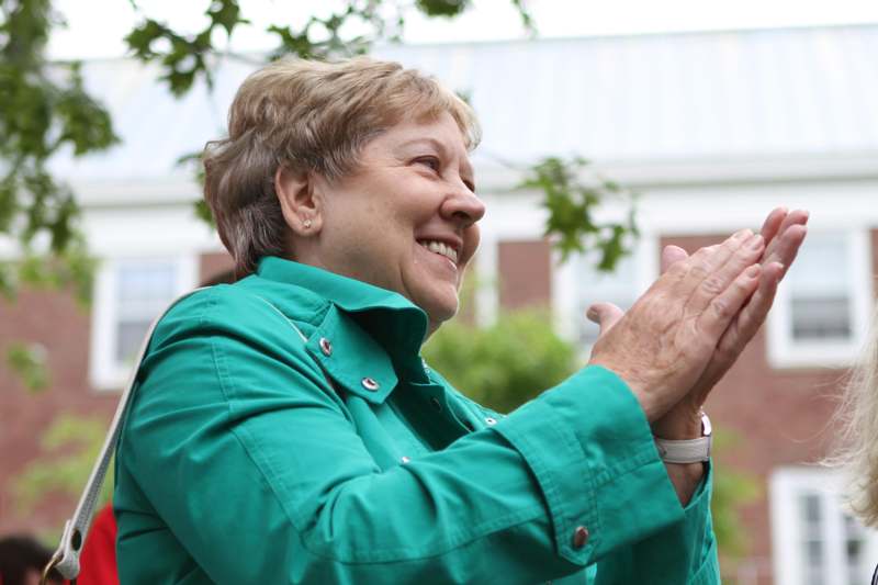 a woman in a green jacket clapping her hands