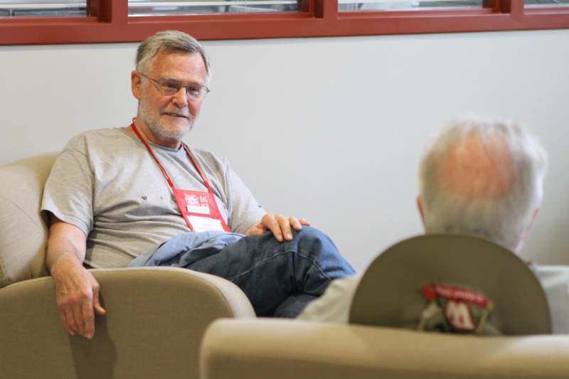 a man sitting in a chair with a man in a red lanyard