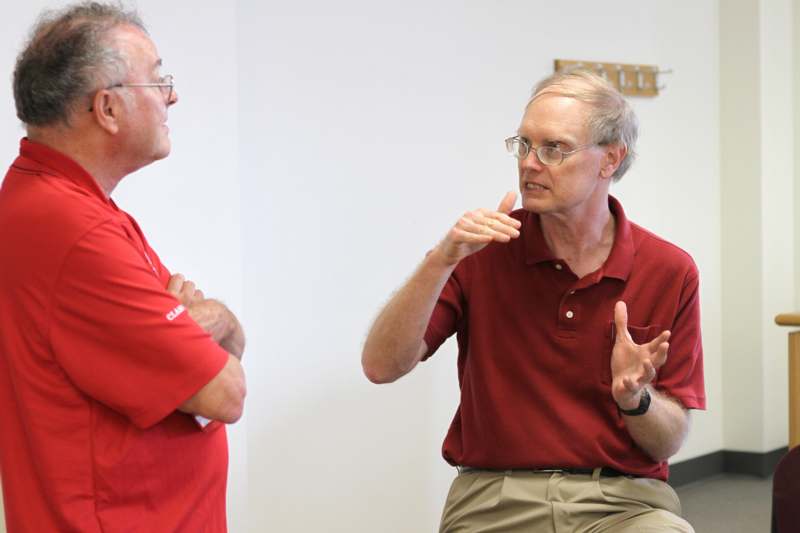 a man in red shirt talking to another man
