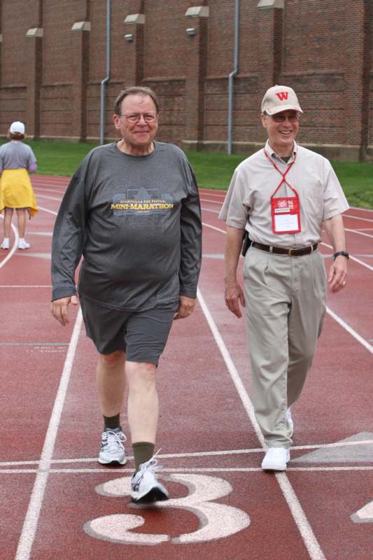 a man walking on a track with a man in a hat