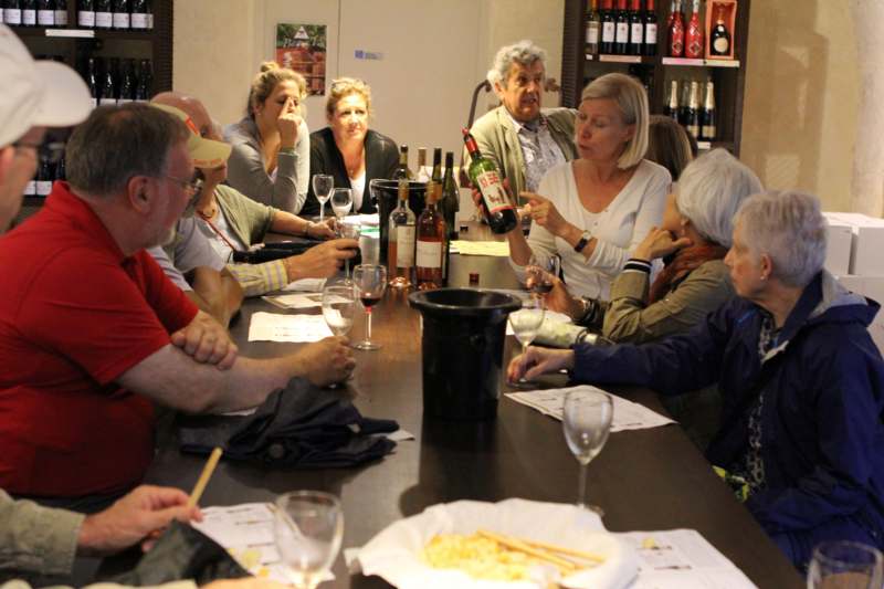 a group of people around a table with wine bottles