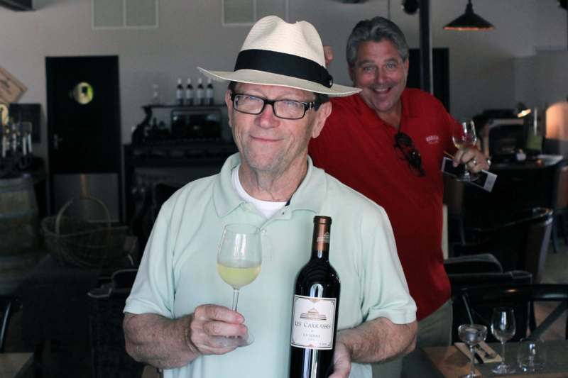 a man holding a wine bottle and a glass of wine