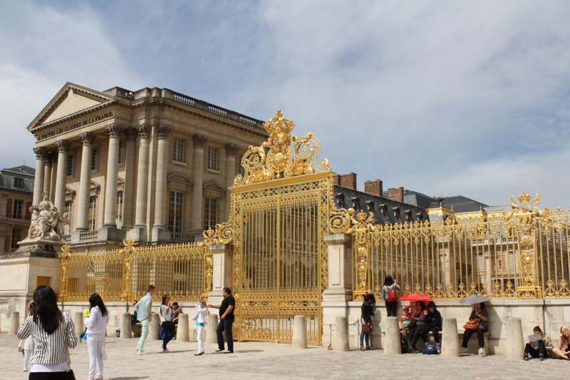 a large gold gate with people walking around