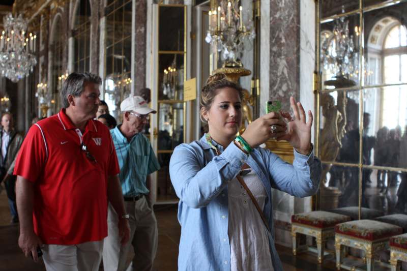a woman taking a picture of a man in a room with chandeliers