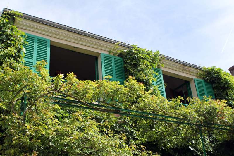 a building with green shutters and trees