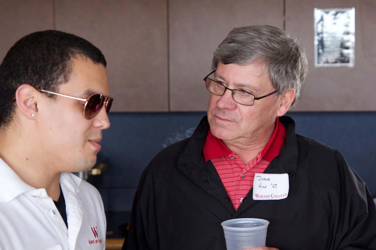 a man wearing glasses and a name tag talking to a man