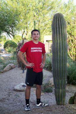 a man standing next to a cactus