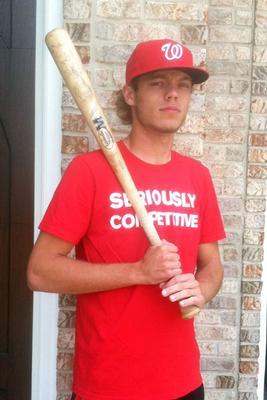 a man in a red shirt and hat holding a baseball bat