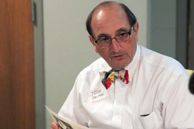 a man wearing glasses and a bow tie reading a newspaper