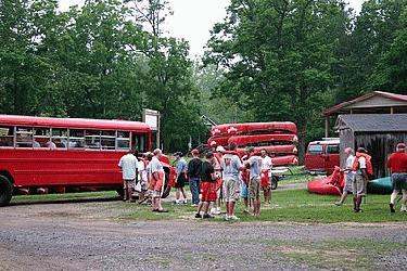 a group of people standing around red buses