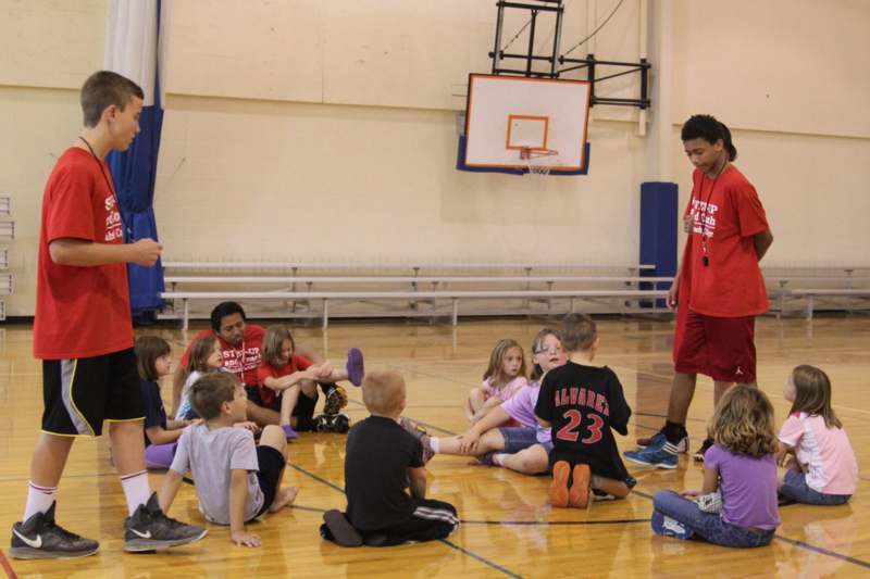 a group of kids sitting on the floor in a gym