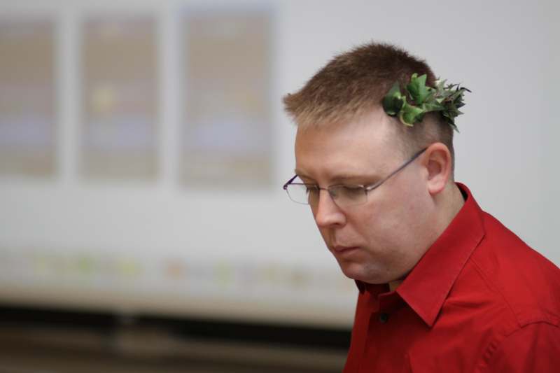 a man wearing glasses and a green leaf on his head