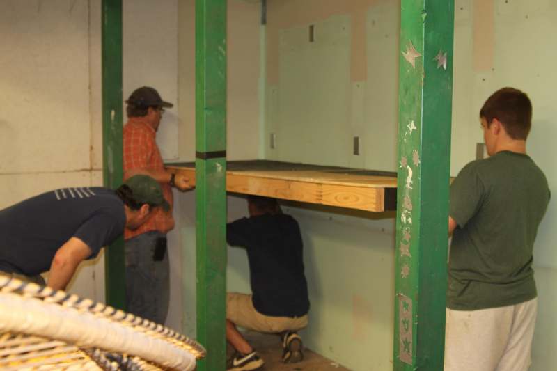 a group of men working on a wood shelf