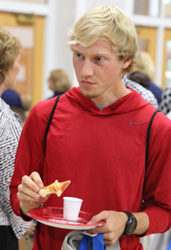 a man in a red shirt eating pizza