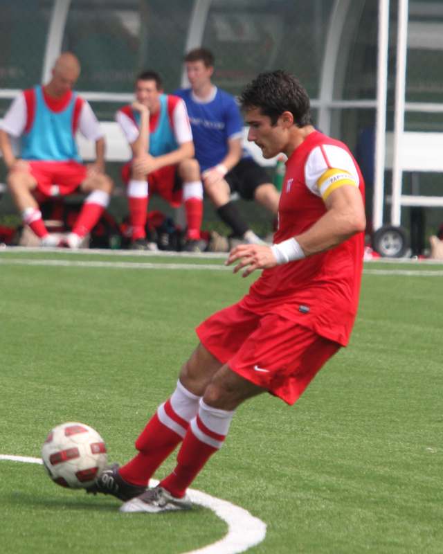a man in red uniform kicking a football ball