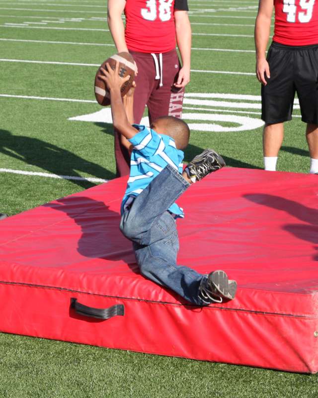 a boy falling on a mat with a football