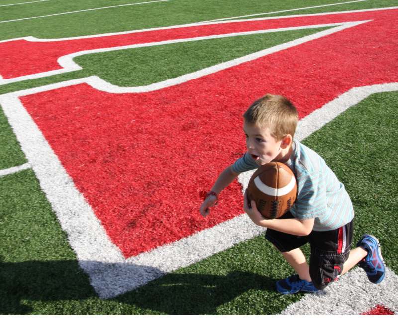a boy holding a football on a football field