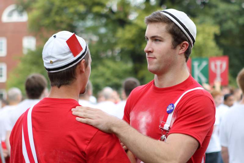 a man in red shirt and white hat with red and white hat holding another man
